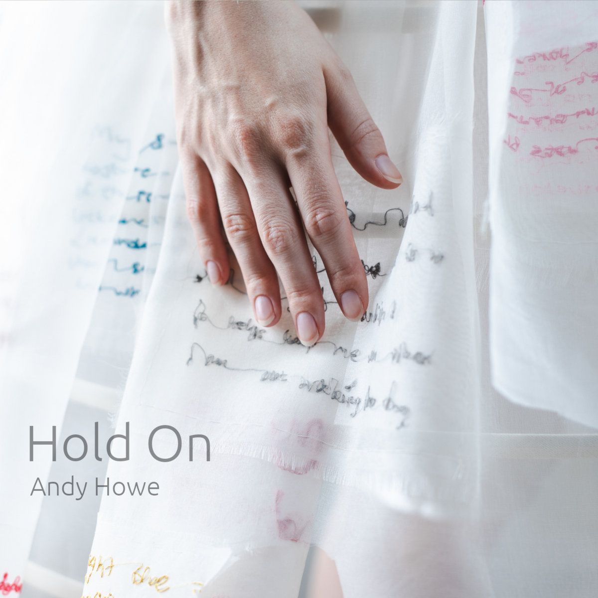 A hand on a dress with writing that you can't quite make out on the dress